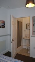 Een badkamer met douche, toilet, wastafel en een spiegel.