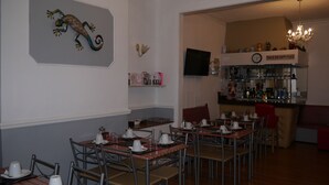 A restaurant with multiple tables and chairs, a bar area with various bottles, and a decorative wall piece. - Hornby House Hotel (Blackpool)