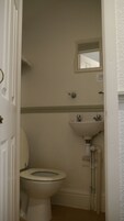Een kleine, eenvoudige badkamer met toilet, wastafel en spiegel.