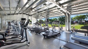 Ein überdachter Fitnessbereich mit Laufbändern, Crosstrainern und stationären Fahrrädern.