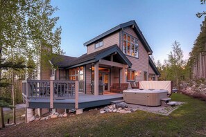 A two-story house with a deck, outdoor seating, and a hot tub.