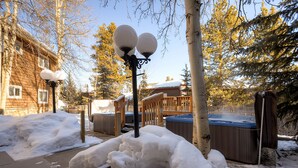 A wooden cabin with a snow-covered deck and hot tubs. - Remodeled Corner Unit with Lots of Light! Walk to Town | PM4A (Breckenridge)