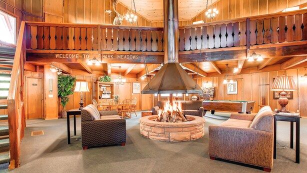 A cozy lobby with a stone fire pit, comfortable seating, and a wooden ceiling with a 'Welcome to Park Meadows' sign. - Remodeled Corner Unit with Lots of Light! Walk to Town | PM4A (Breckenridge)