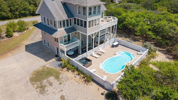 A multi-story house with a large balcony, a swimming pool, and a view of the ocean. - Private pool open and can be heated through Thanksgiving! Pet Friendly! (Corolla)