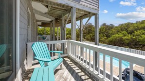 A wooden deck with a pool, a covered area with chairs, and a view of trees. - Private pool open and can be heated through Thanksgiving! Pet Friendly! (Corolla)