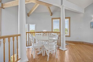 A spacious room with a wooden floor, white walls, and a round table with chairs. - Private pool open and can be heated through Thanksgiving! Pet Friendly! (Corolla)