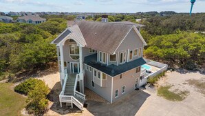 A large two-story house with a front porch, a swimming pool, and a driveway. - Private pool open and can be heated through Thanksgiving! Pet Friendly! (Corolla)
