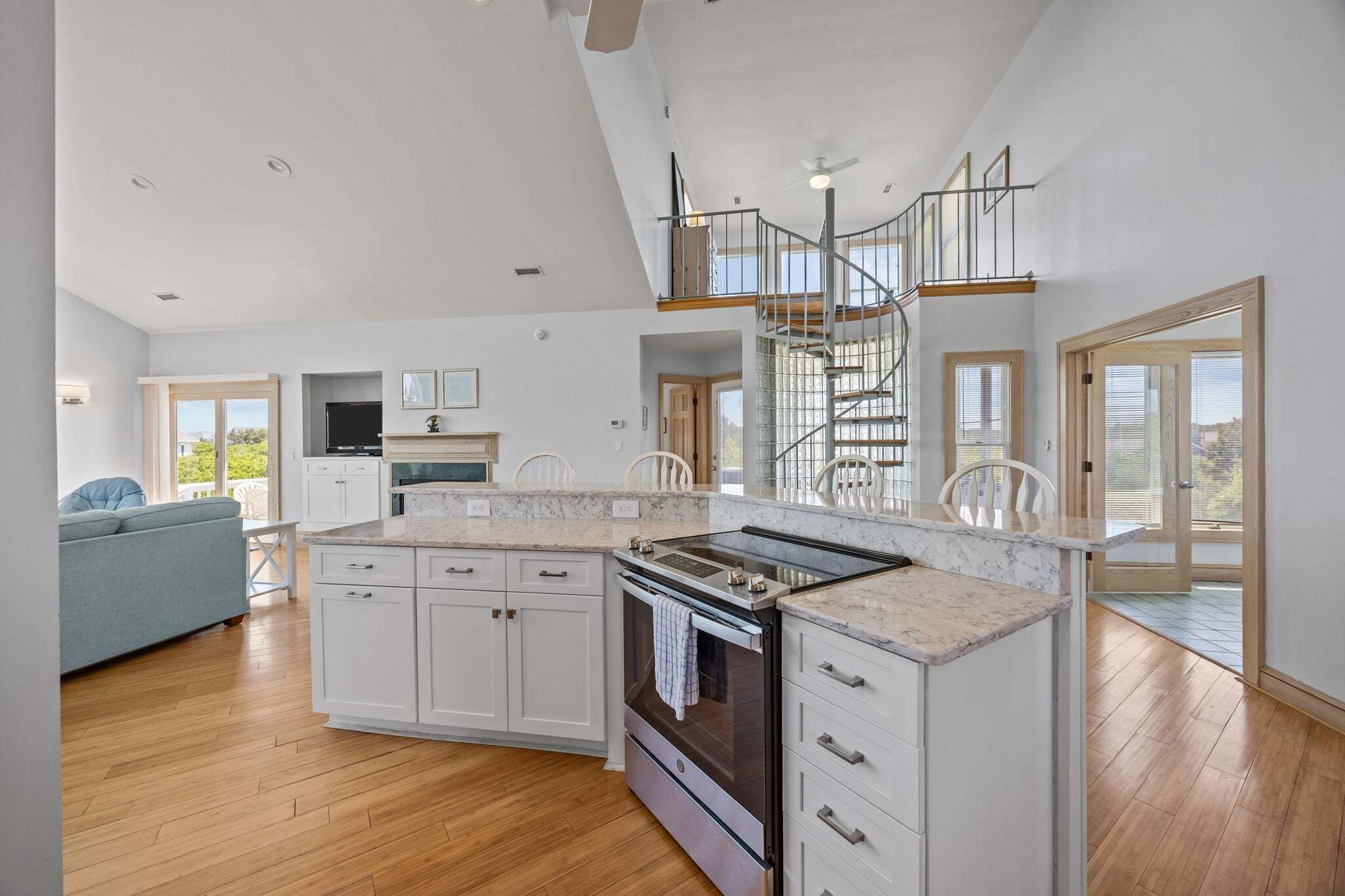 A spacious kitchen with white cabinets, a central island, and a built-in oven.