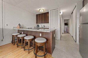 Une cuisine dotée d’un îlot central, de tabourets de bar, de meubles en bois et d’un luminaire moderne.