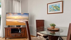 A living room with a flat-screen TV, a glass table, and a framed picture on the wall.