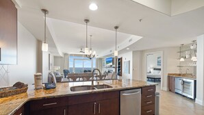 A modern kitchen with a central island, stainless steel appliances, and a dining area with a view. - Turquoise Place 1205C by Liquid Life (Orange Beach)