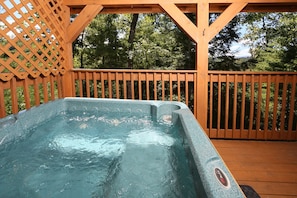 A hot tub on a wooden deck with a wooden lattice fence and trees in the background. - Secluded | Pet Friendly | Pool Table | Arcade | Hot Tub | WiFi (SEVIERVILLE)