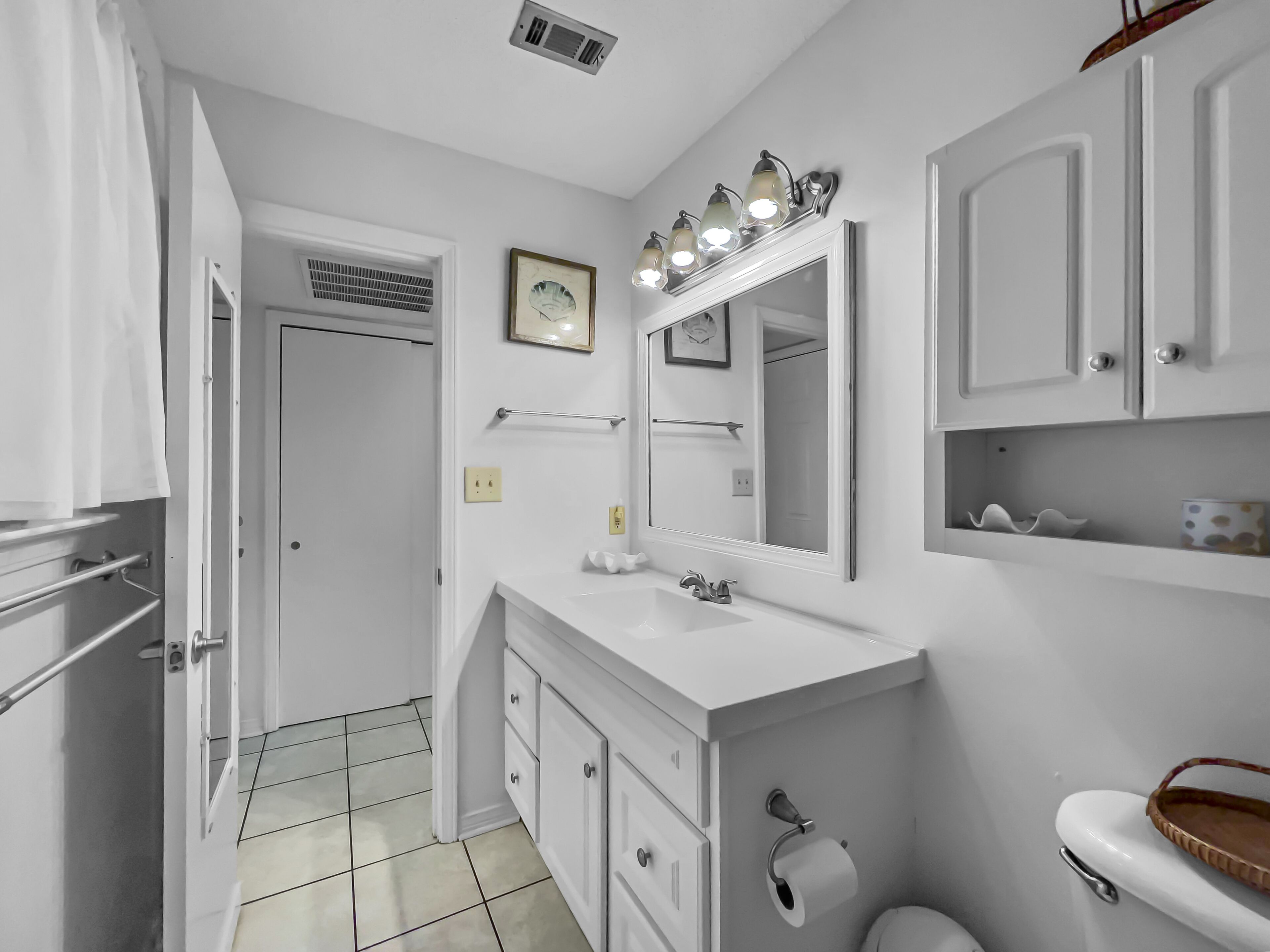 Un bagno con un mobile lavabo bianco, uno specchio illuminato, un water e uno spazio doccia.