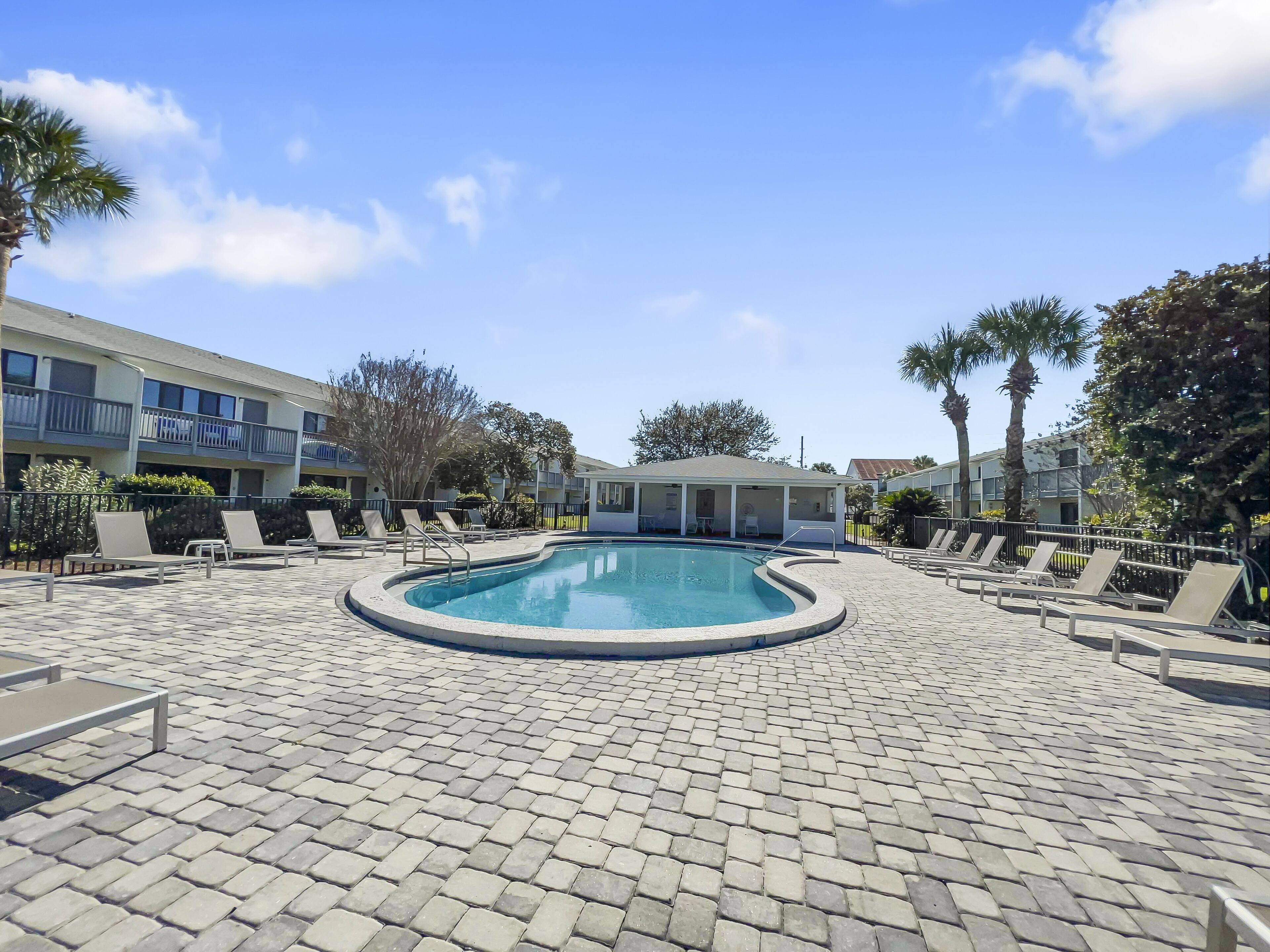 A pool area with lounge chairs and a covered seating area.