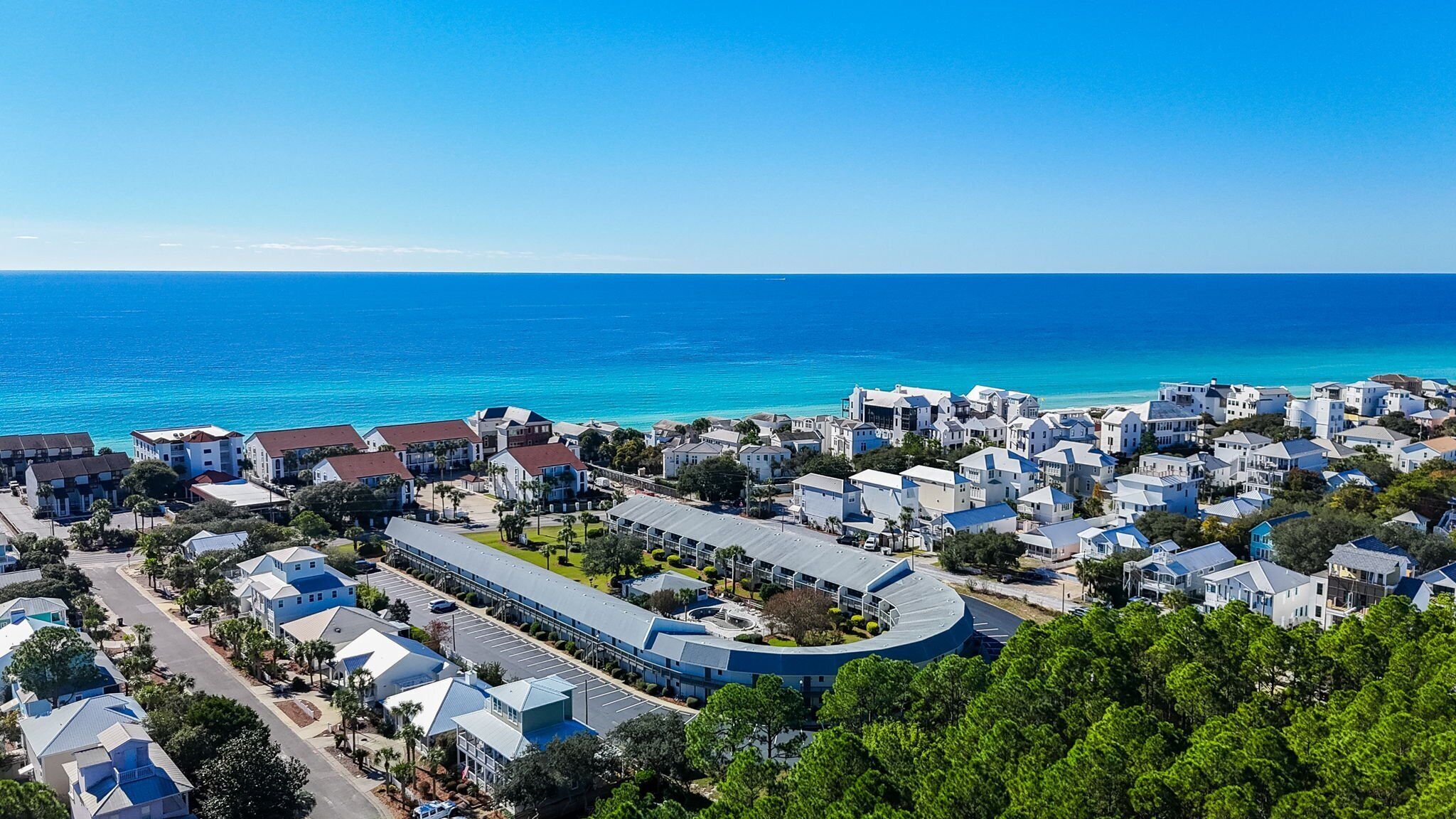 Un quartier résidentiel situé sur la côte, composé d’un mélange de maisons unifamiliales et d’immeubles d’appartements, avec une route sinueuse et une vue dégagée sur l’océan.