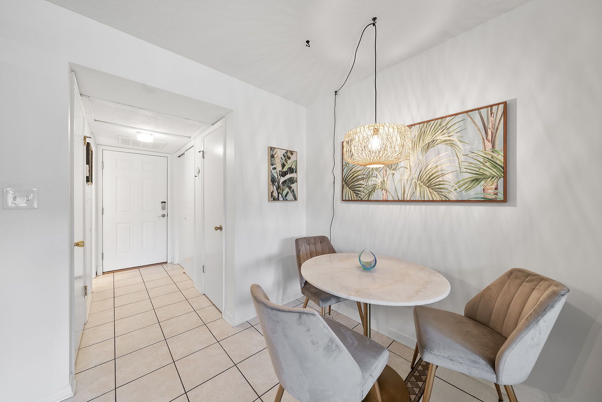 A dining area with a round table, two chairs, and a wall-mounted light fixture.