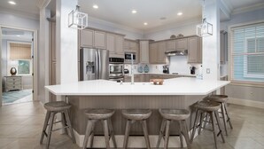 A modern kitchen with a large island, stainless steel appliances, and wooden bar stools.