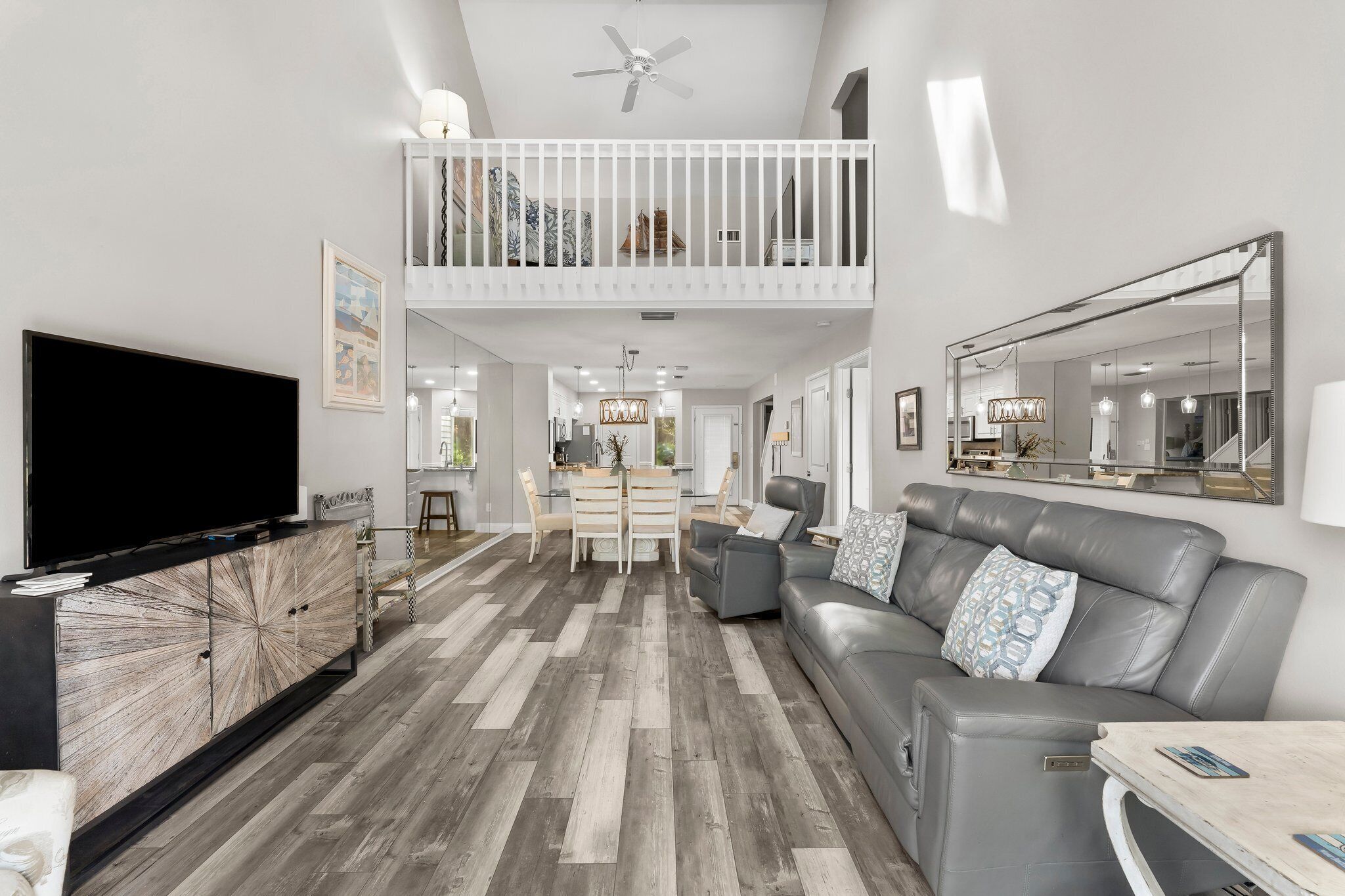 A modern living room with a TV, grey sofa, and a dining area with a table and chairs.