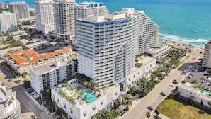 Un hotel modern amb balcons múltiples, una piscina i vista a l'oceà.