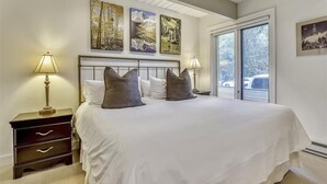 Ein Schlafzimmer mit einem großen Bett, zwei Nachttischen und drei an der Wand befestigten Bildern.