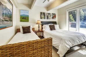 A hotel room with two beds, a large window with a mountain view, and artwork on the walls.