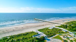 An aerial view of a beach with a pier extending into the ocean, a sandy beach, and a park area with pathways and greenery. - Modern Condo, Pool, Close to Beach, Restaurants & Shops - 101A Oceanside (Isle Of Palms)