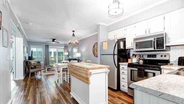 A spacious kitchen with white cabinets, a wooden island, and modern appliances. - Modern Condo, Pool, Close to Beach, Restaurants & Shops - 101A Oceanside (Isle Of Palms)