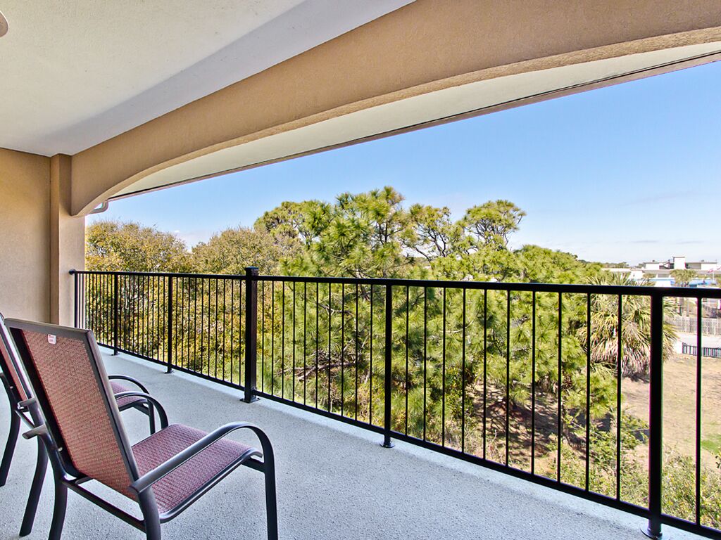 A balcony with two chairs and a view of trees and buildings.
