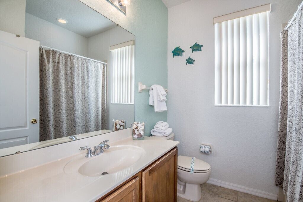 Une salle de bain équipée d’un lavabo, d’un miroir, de toilettes et d’une décoration murale représentant des poissons.