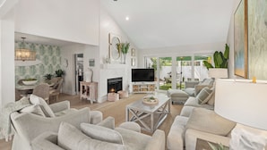 A spacious living room with a fireplace, comfortable seating, and a large TV. - Beautiful Renovation~Golf Course View~Golf Cart,Free Activities, Fenced Patio (Miramar Beach)
