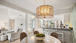 A modern living room with a round dining table, a large woven light fixture, and a view into the kitchen. - Beautiful Renovation~Golf Course View~Golf Cart,Free Activities, Fenced Patio (Miramar Beach)