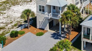 Une maison à deux étages avec un balcon, une piscine et, au loin, une plage de sable.