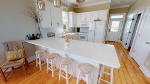 Une cuisine dotée d’un grand îlot central, de meubles blancs et d’un plancher en bois.
