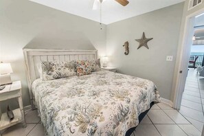 Une chambre à coucher avec un lit, une table de chevet, une lampe, une décoration en forme d’étoile et un ventilateur de plafond.