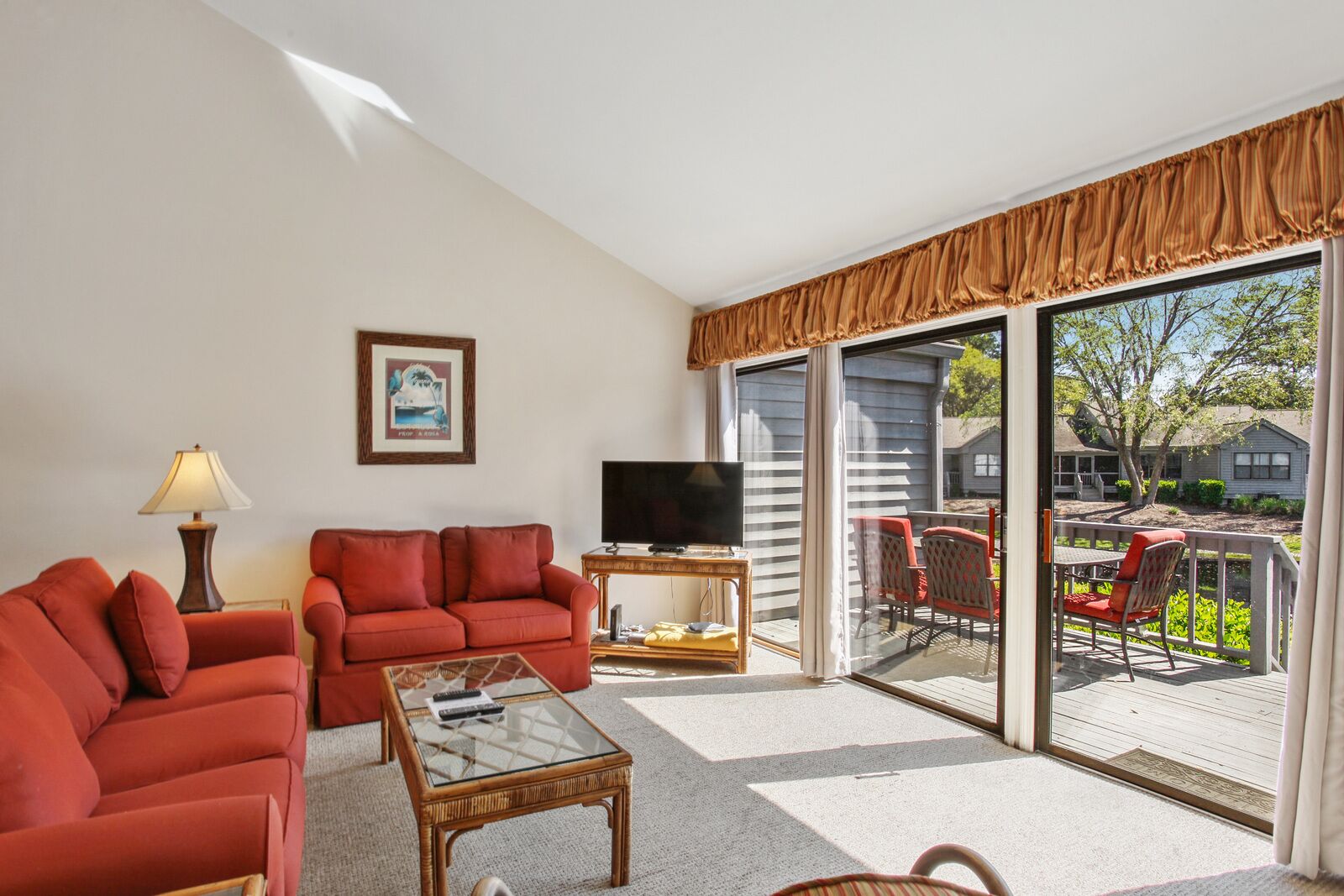 A living room with a sofa, a coffee table, a TV, and a large sliding glass door leading to an outdoor patio.