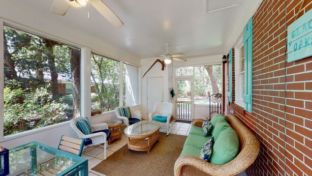 Habitació il·luminada pel sol amb mobles de vimet, una taula de vidre i vista a l'exterior.