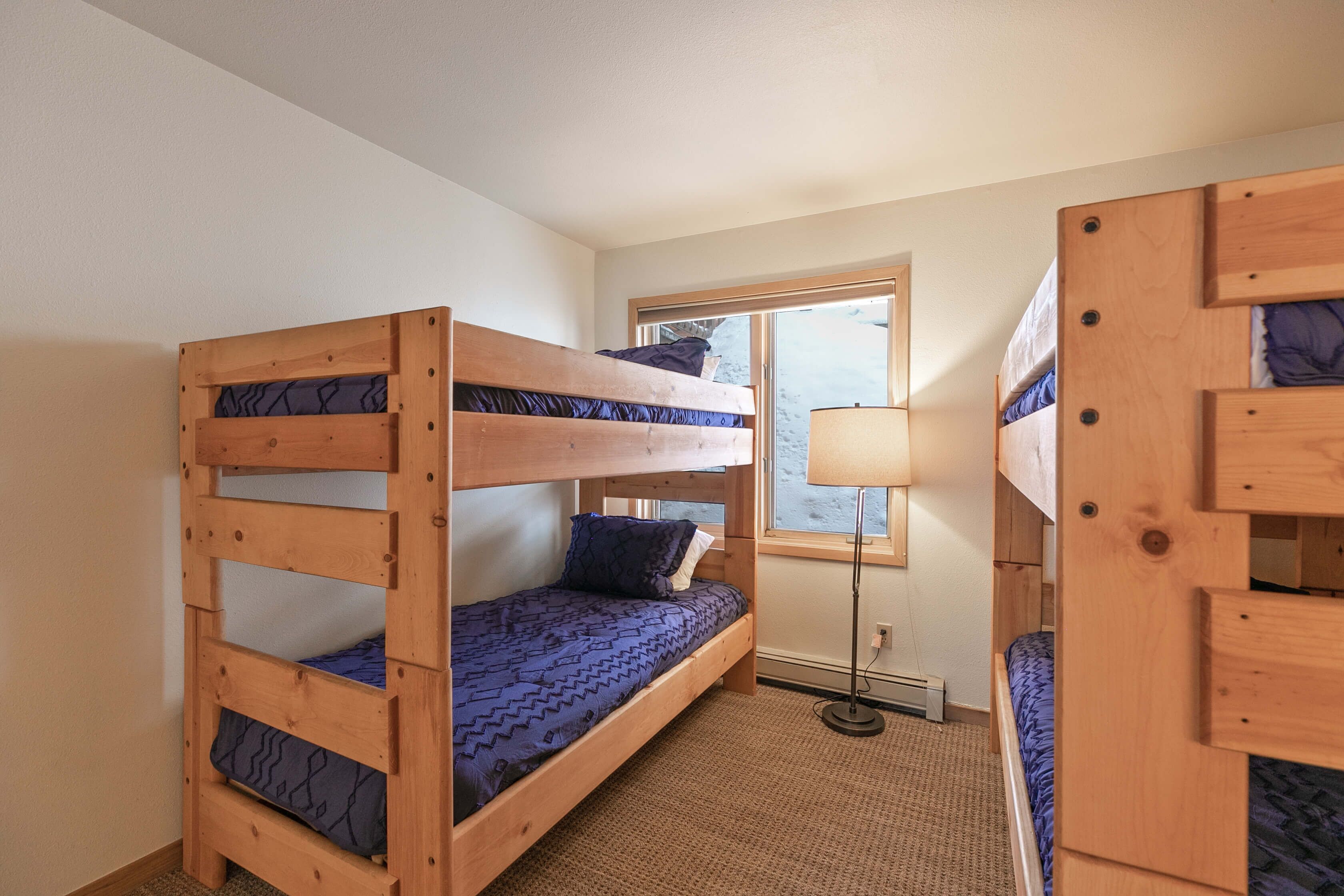 Une chambre avec deux lits superposés, une fenêtre et une lampe sur pied.