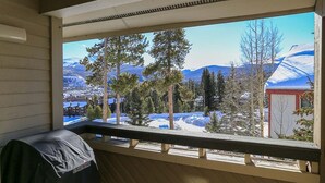 Un portico riparato con vista su un paesaggio innevato, tra cui alberi e montagne.