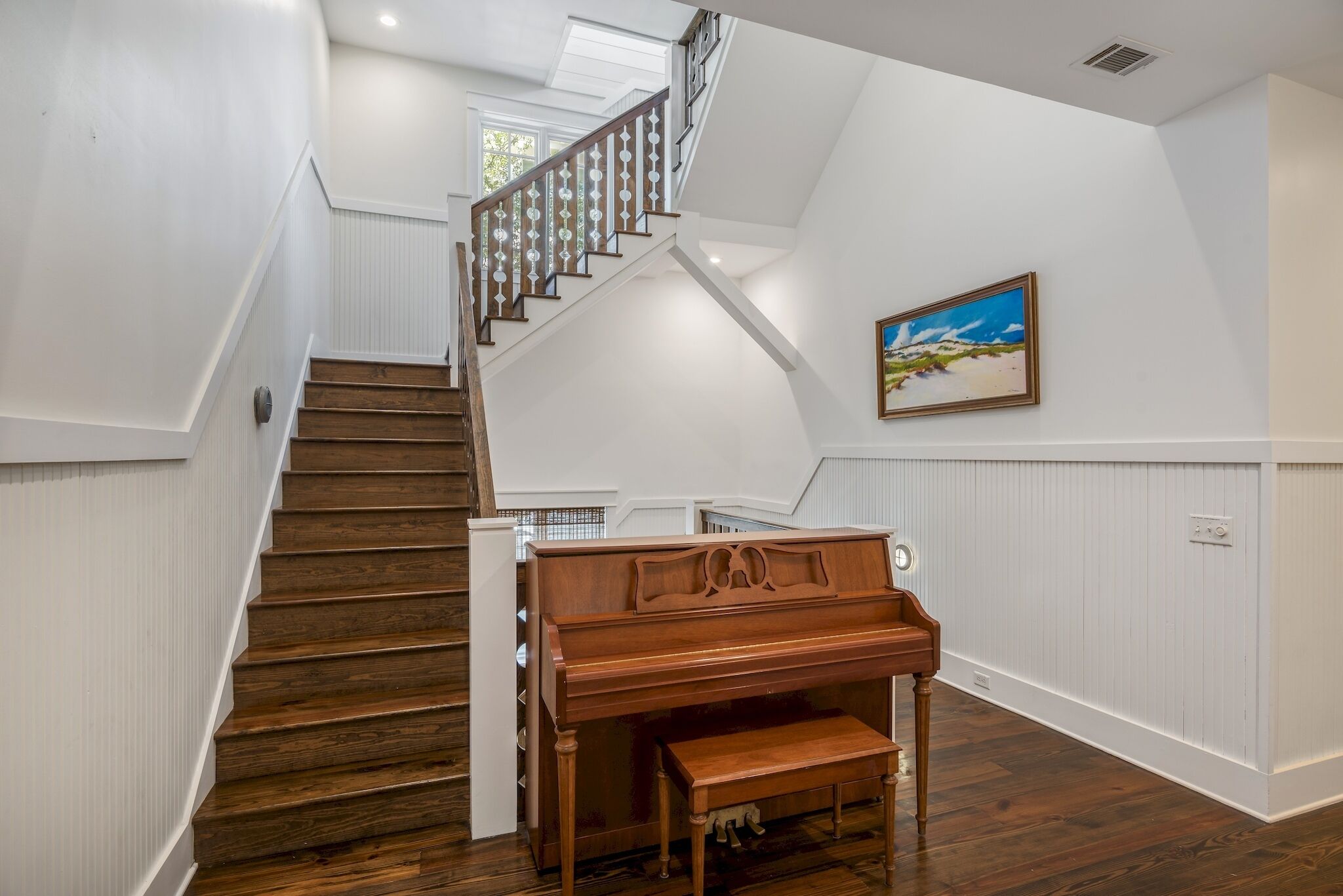 A grand staircase with wooden steps and a wooden piano bench at the bottom.