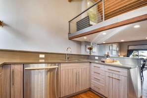 A modern kitchen with a stainless steel refrigerator, wooden cabinets, and a built-in oven.