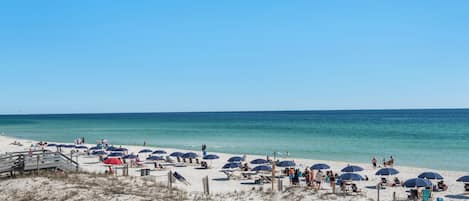 Relax on the beach with lounge chairs and umbrellas, accessible via a wooden walkway.
