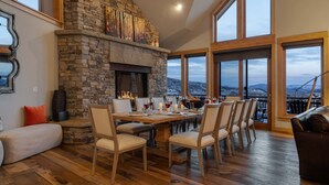 A dining area with a stone fireplace, wooden dining table, and chairs. - Magnificent + Hot Tub + Close to Skiing - Falconhead Lodge - North (Steamboat Springs)
