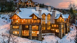 A large, multi-story lodge with stone walls and wooden balconies, surrounded by snow. - Magnificent + Hot Tub + Close to Skiing - Falconhead Lodge - North (Steamboat Springs)