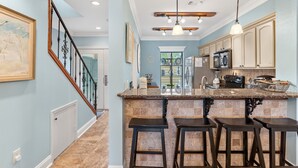 A kitchen with a central island, bar stools, and a ceiling fan. - Renovated Beach Villa w/GOLF CART, Lakeside, Beach, Pool/Hot Tub, Tram, Grill (Miramar Beach)