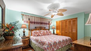 A bedroom with a bed, wooden wardrobe, bedside lamps, and a ceiling fan. - Island Charm: Kihei Beach #305, Beachfront Condo Offers Spectacular Ocean Views! (Kihei, Maui)