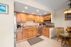 A modern kitchen with wooden cabinets, stainless steel appliances, and a glass dining table.