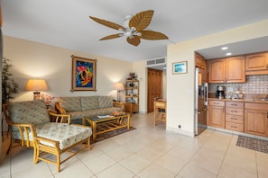 Sala de estar com sofá, cadeiras, mesa de centro e ventilador de teto.
