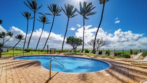A swimming pool with a brick deck, surrounded by palm trees and lounge chairs. - Island Charm: Kihei Beach #305, Beachfront Condo Offers Spectacular Ocean Views! (Kihei, Maui)