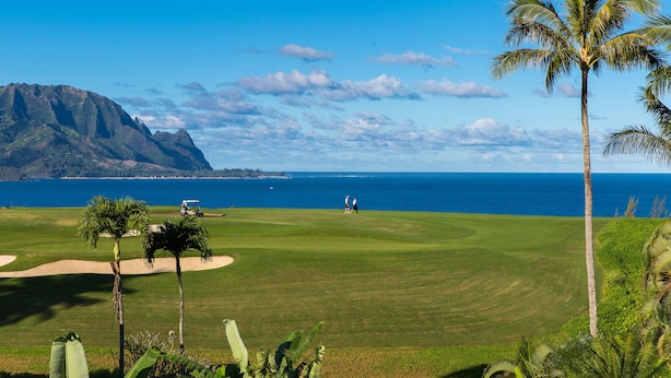 A golf course with a clear view of the ocean and mountains in the background. - Emmalani Court #225 Fabulous Views!  Air Conditioning in Both Bedrooms (Princeville)