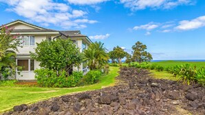 A house with a garden and a view of the ocean. - Emmalani Court #225 Fabulous Views!  Air Conditioning in Both Bedrooms (Princeville)